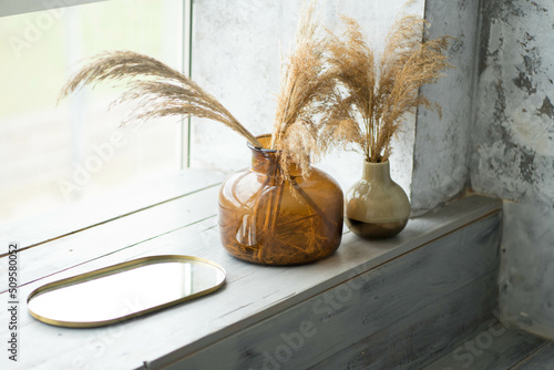 two glass vases are on the windowsill
