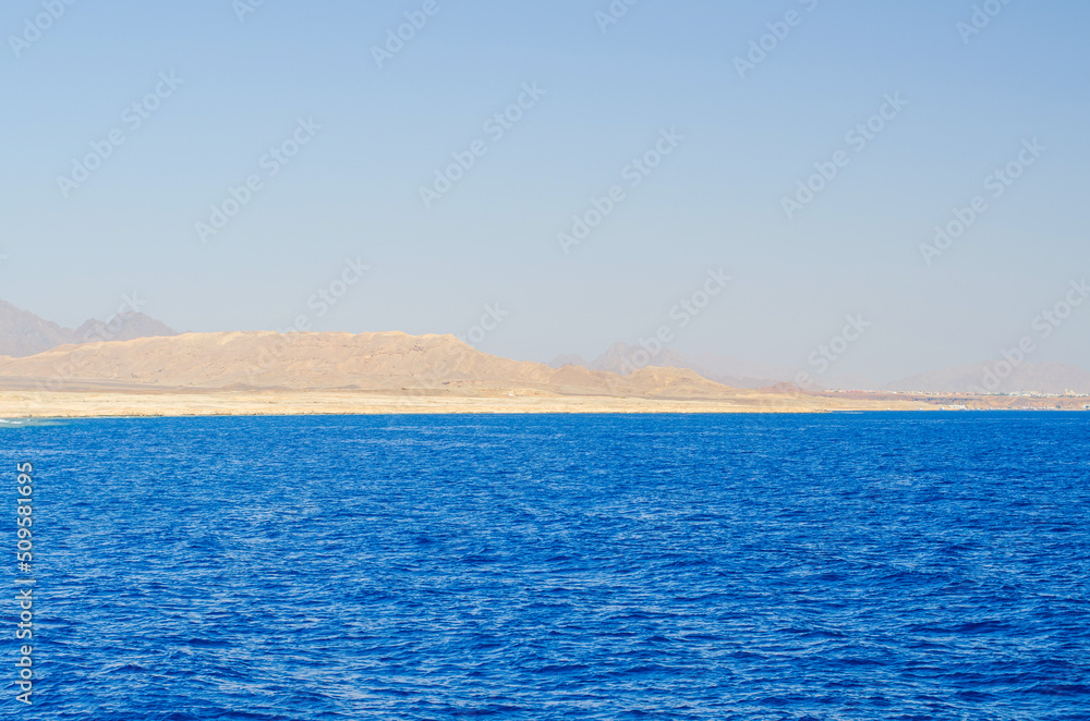 Seaview to the island with white sand beach. Calm blue sea water with waves on early morning time.