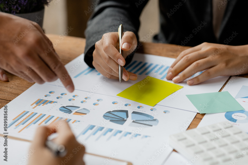 A group of people pointing to papers on a table in a conference room, a financial analyst attending a company audit meeting with the finance and accounting department. Meeting concept.