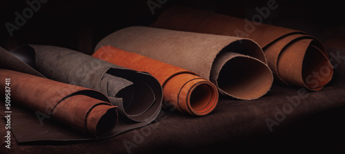Foto Different rolls of multi-colored natural color leather on rack in workshop