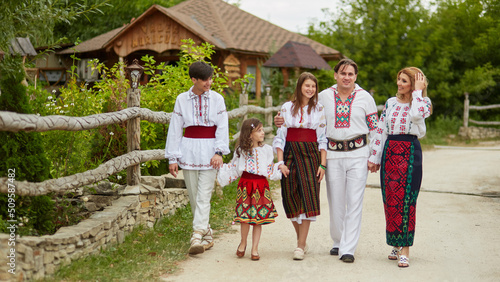 Obraz na plátně Full length image Happy family with kids in traditional romanian clothes in a countryside