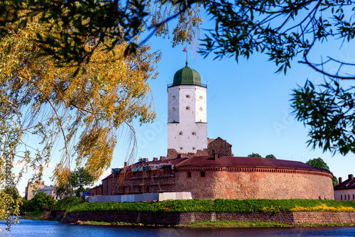 Medieval fortress in Vyborg. Castle on the water against the background of a blue sky with foliage photo