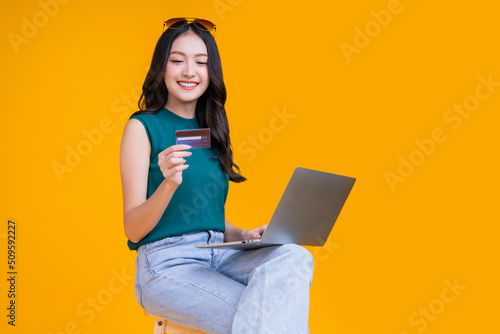 smart asian woman hand using credit card laptop with smile confident and cheerful studio shot,asia young adult woman sit on stool hand gesture hold credit care cashless payment business ideas