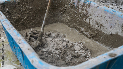 Mixing tile adhesive or cement with a power drill for repair works on construction site. Waiting to be mixed with cement. © kalyanby