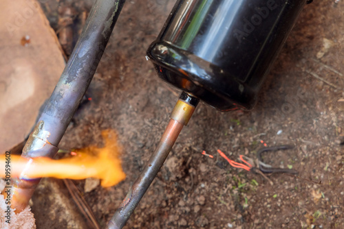 Wallpaper Mural HVAC plumber technician soldering a copper pipe joint for central air conditioning with replacement old outside air conditioner unit Torontodigital.ca