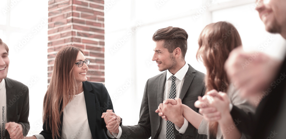 © ASDF - Business group in a circle holding hands indoors