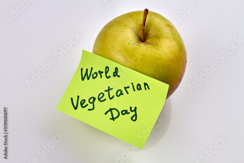 Green ripe apple with sticker note isolated on white background. World vegetarian day.