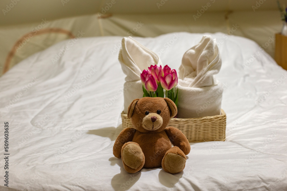 Close up photo of bear doll on bed and blurred background.