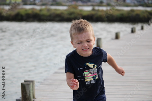 enfant blond garçon sur un ponton dans la mer à bages