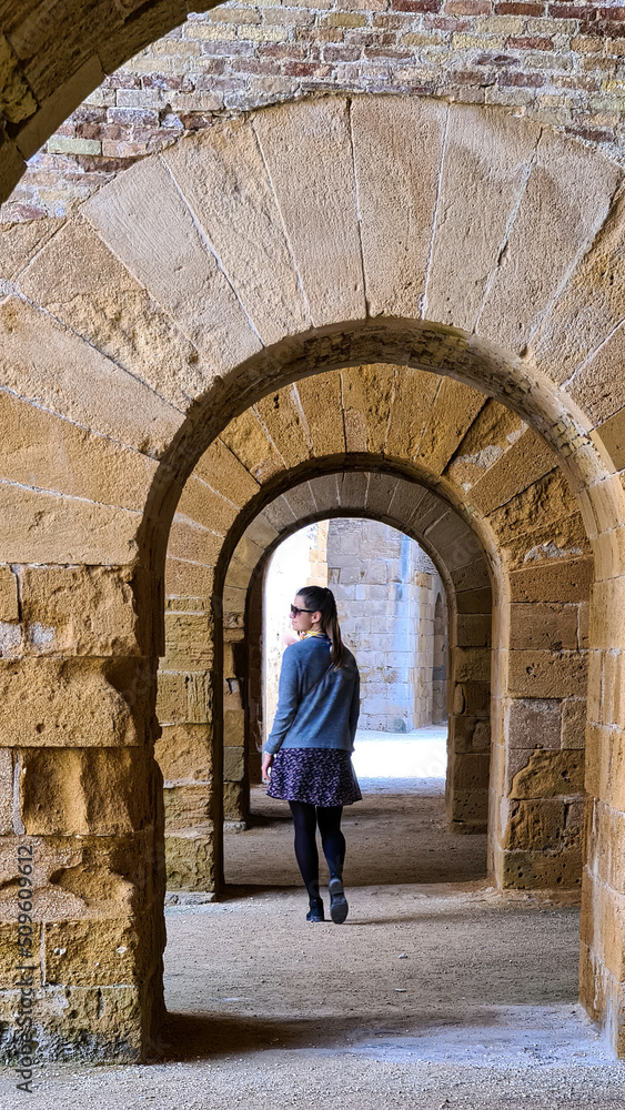Tourist woman walking through inside vaults of the Castello Maniace. Interior of ancient citadel fortress Maniace Castle on island of Ortygia in Syracuse, Sicily, Italy, Europe EU. UNESCO Site. Tunnel
