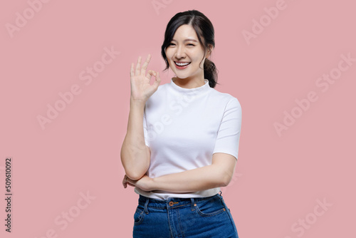 Obraz na plátně Happy young Asian woman feeling happiness and gesture showing OK hand sign on isolated pink background