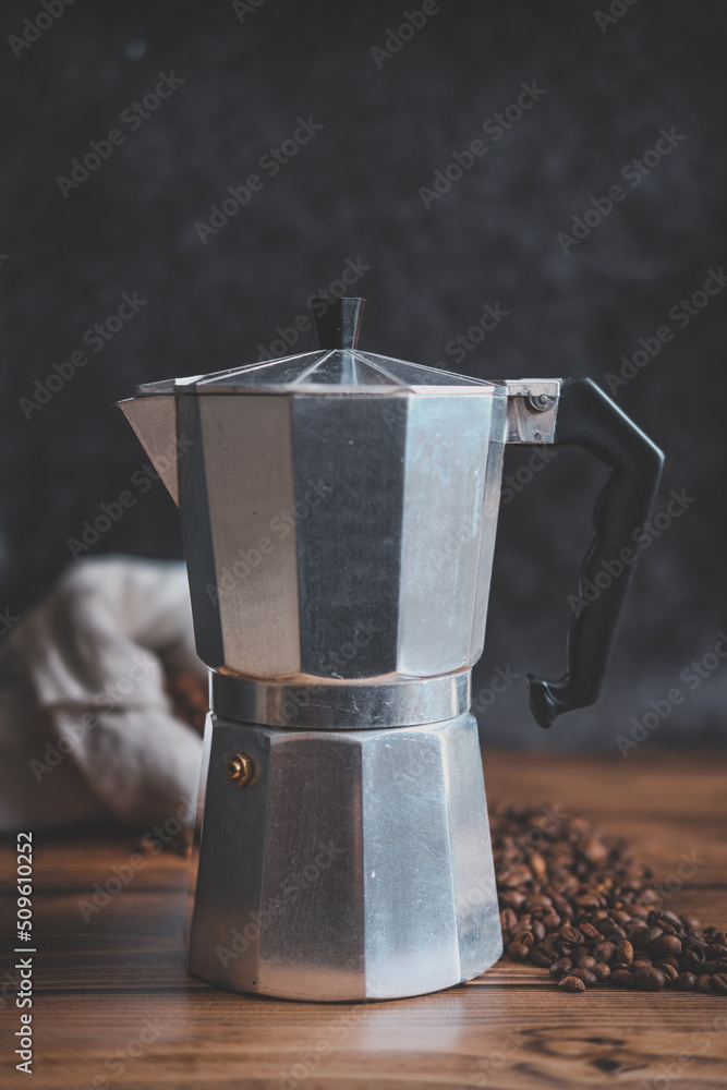 Old steel coffee pot on the wooden table and black background