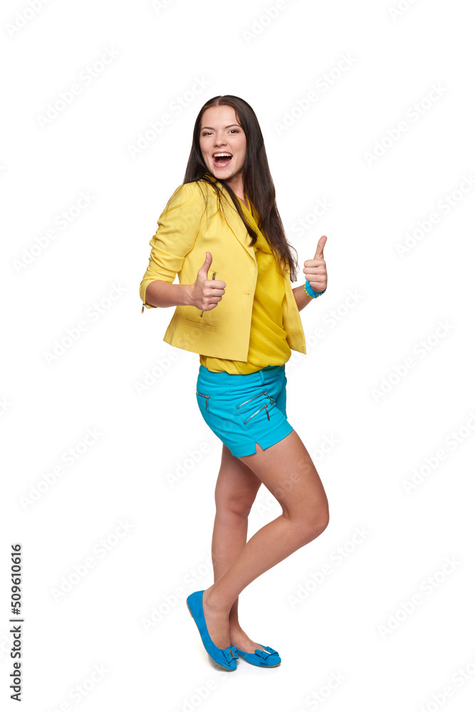 Full length of happy joyful young girl in yellow and blue clothes gesturing thumbs up Full length of happy joyful young girl in yellow and blue clothes gesturing thumbs up