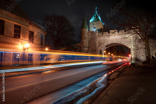 St-Louis gate, arch in fortifications of Quebec city at night, while cars and bus are passing by, QC, Canada