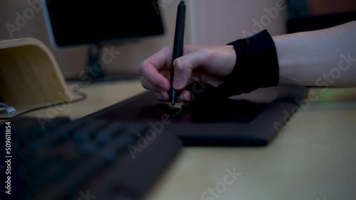 Close-up of hand drawing on a digital tablet with pen. Professional retoucher working on graphic tablet.