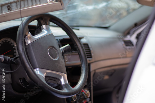 Close-up of the steering wheel of a car after an accident. The driver's airbags did not deploy. Soft focus. Broken windshield with steering wheel. Vehicle interior. Black dashboard and steering wheel. © Yevhen Roshchyn