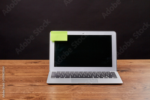 Macbook air laptop and attached sticky note for copy space. Notebook device on wooden desk.