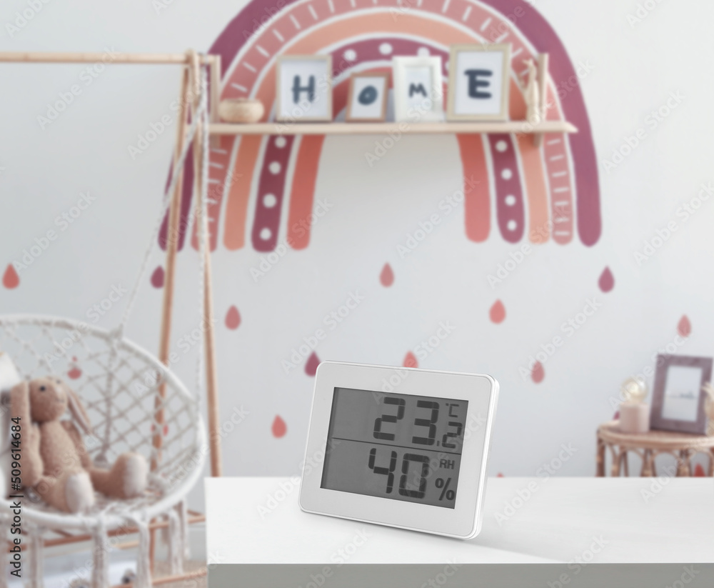Digital hygrometer with thermometer on white table in children's room. Optimal humidity level for kids - obrazy, fototapety, plakaty 