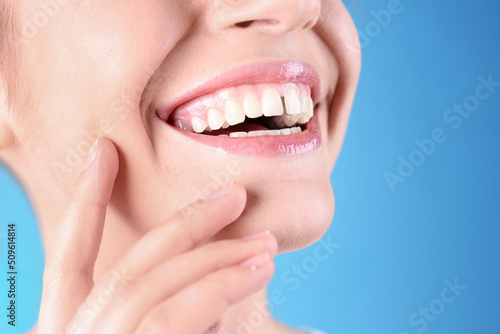 Woman with diastema between upper front teeth on light blue background, closeup photo