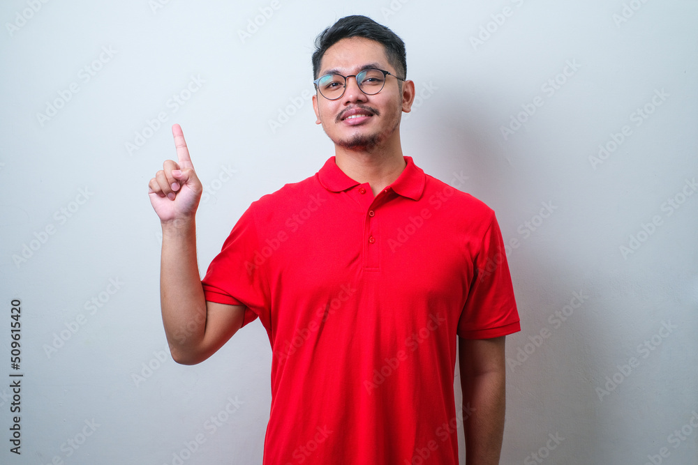 Young handsome asian man wearing casual shirt pointing something on his side with his hand Young handsome asian man wearing casual shirt pointing something on his side with his hand