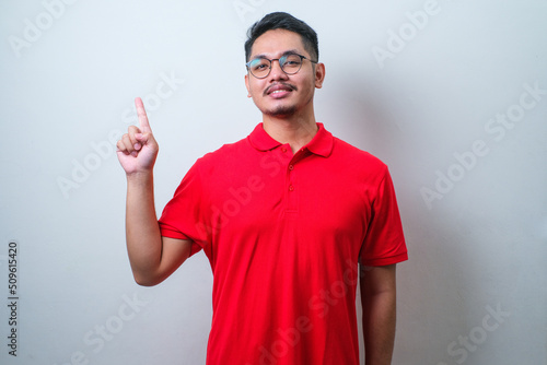 Young handsome asian man wearing casual shirt pointing something on his side with his hand