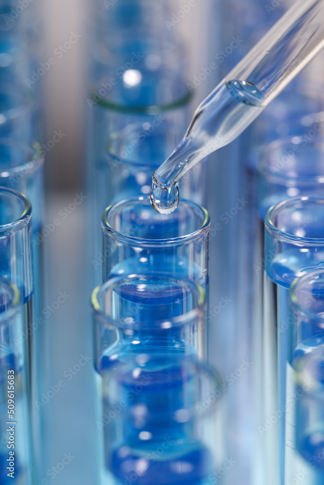 Dripping reagent into test tube with blue liquid on light background, closeup. Laboratory analysis Dripping reagent into test tube with blue liquid on light background, closeup. Laboratory analysis