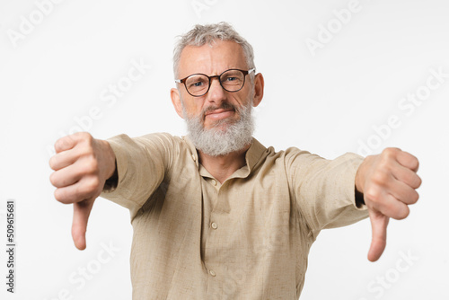 Photos Sad disappointed mature middle-aged caucasian man with grey hair showing thumb down for disagreement isolated in white background