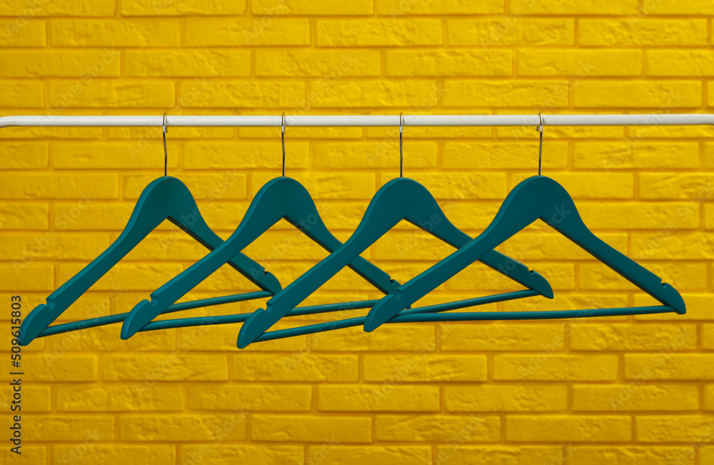 Wardrobe rack with many hangers near yellow brick wall Wardrobe rack with many hangers near yellow brick wall