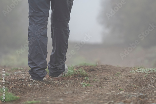 Selective focus shot of footsteps of person walking in nature in foggy weather.
