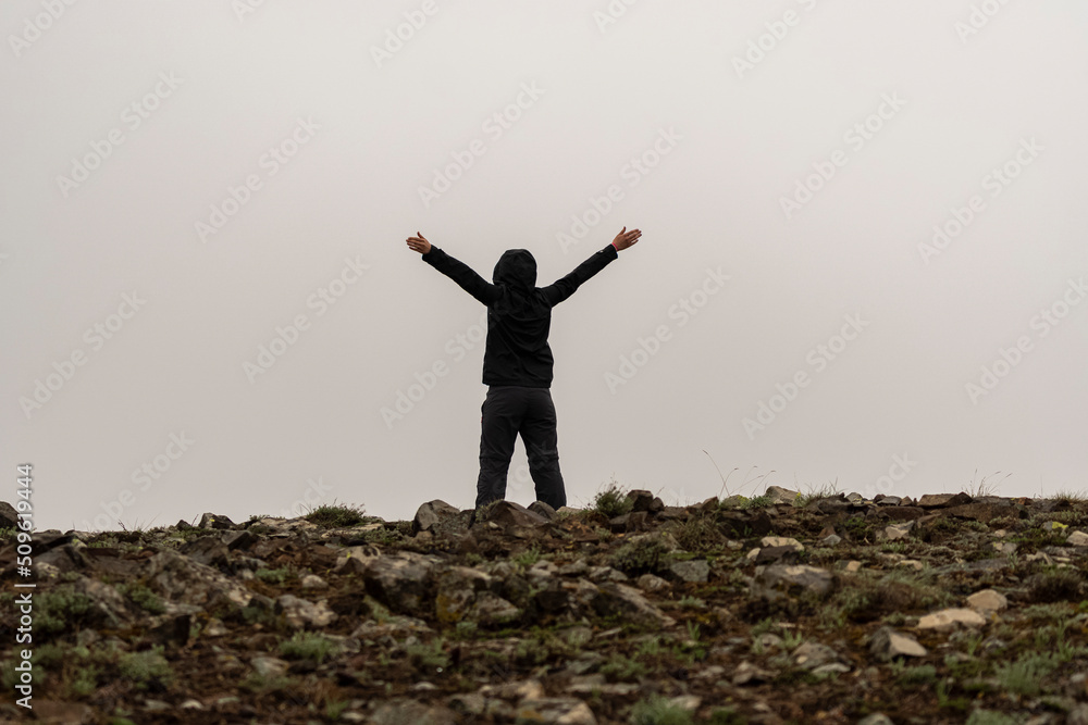 Selective focus shot of free woman raising hands on rocky terrain in foggy weather. Selective focus shot of free woman raising hands on rocky terrain in foggy weather.