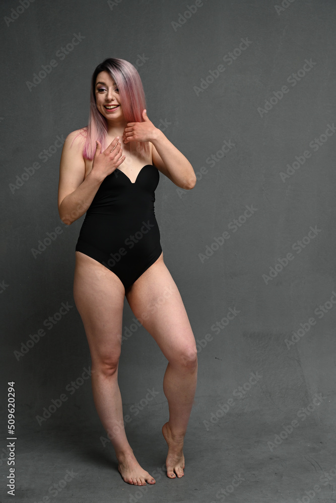 Full length portrait of a smiling girl with pink hair in a black bodysuit looks away