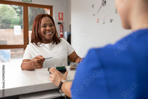 A black woman smiles with joy holding her credit card before paying in return for the good service she has received at the dental clinic