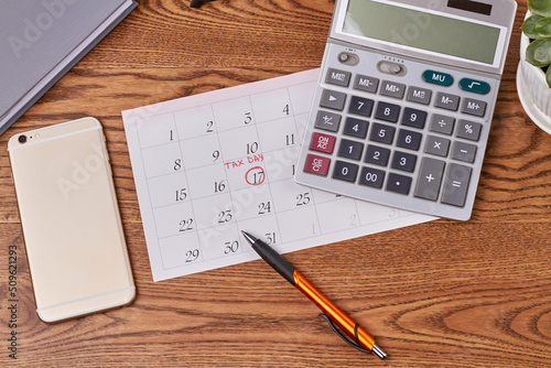 Business accauntant workplace top view flat lay. Calculator with oen and phone on brown wooden desk. photo