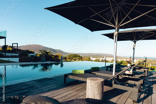 View of luxury contemporary outdoor wooden patio with swimming pool with deck chairs and umbrellas © WavebreakMediaMicro
