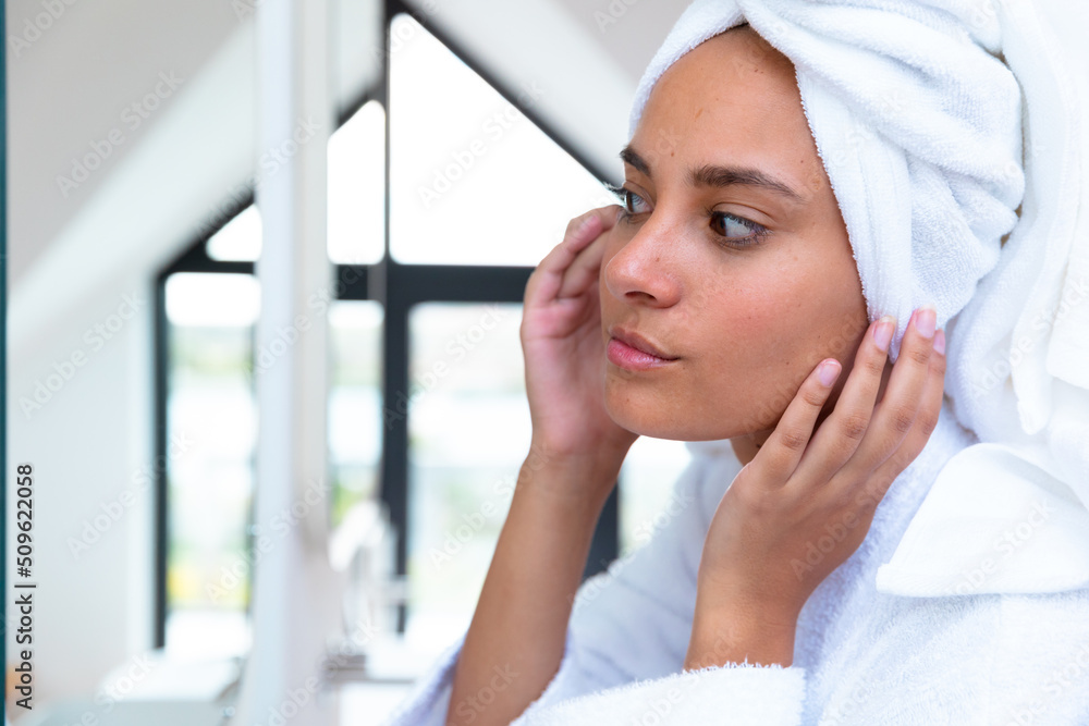 Caucasian woman in a bathrobe looking in the mirror at home Caucasian woman in a bathrobe looking in the mirror at home