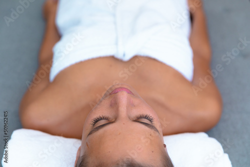 Overhead view of caucasian young woman in a bathrobe relaxing on the massage table