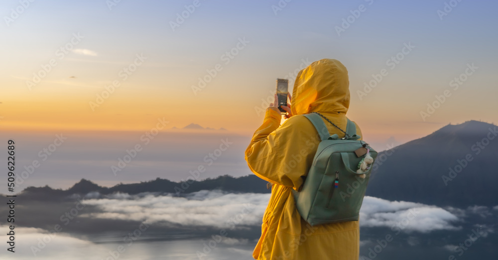 woman watching sunrise taking a photo woman watching sunrise taking a photo
