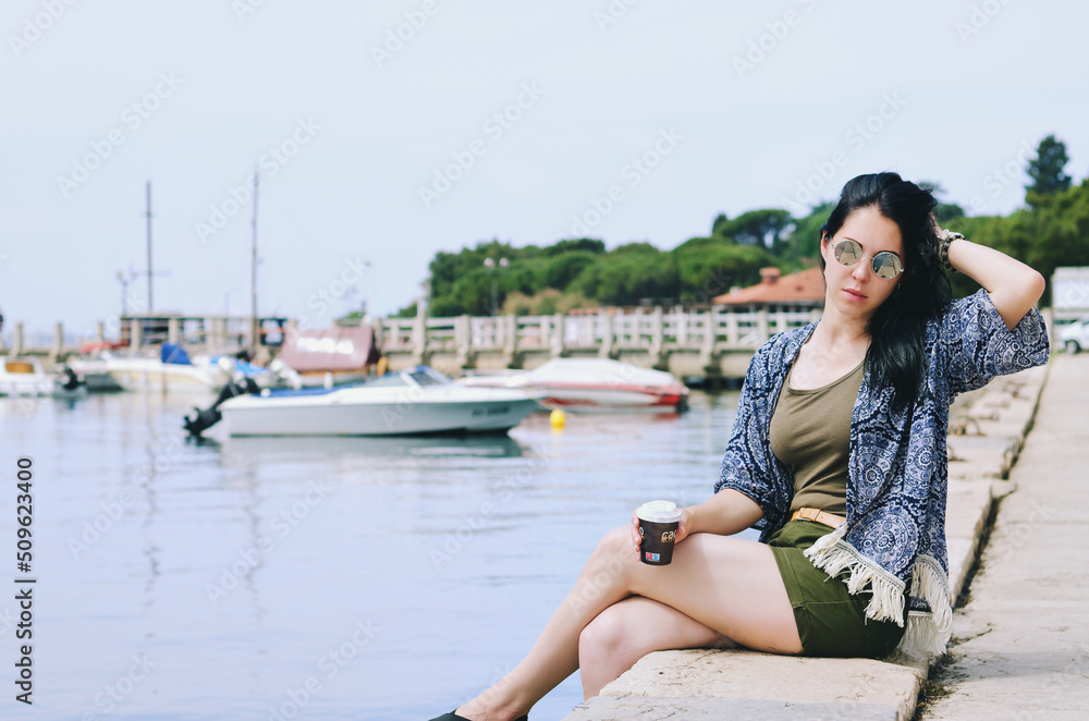 Lifestyle Portrait. Beautiful happy woman walking, relaxing, enjoying in sunny day at beach. Summer. Drinking coffee. Adriatic Sea