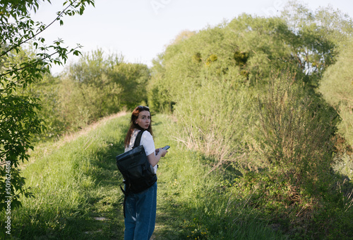 portrait of a young woman with a backpack and phone in nature © YAROVA