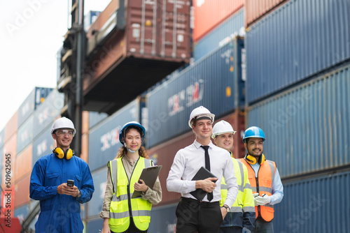 Group of engineer worker and manager standing in the shipping yard container. Truck lifting and forklift behind. Import, export product. Manufacturing transport and global business concept