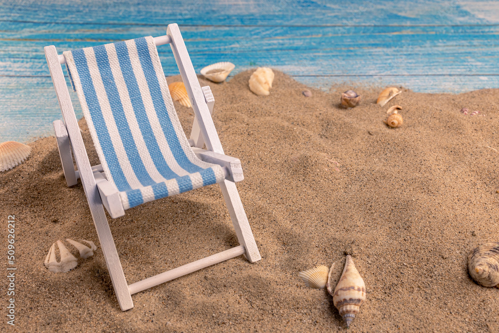 Sun lounger and seashells on the sand on a blue background Sun lounger and seashells on the sand on a blue background
