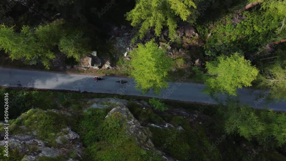 Man riding a bicycle on a mountain road in the forest, view from above. Drone footage 4K. Switzerland near to Zermatt. Man riding a bicycle on a mountain road in the forest, view from above. Drone footage 4K. Switzerland near to Zermatt.