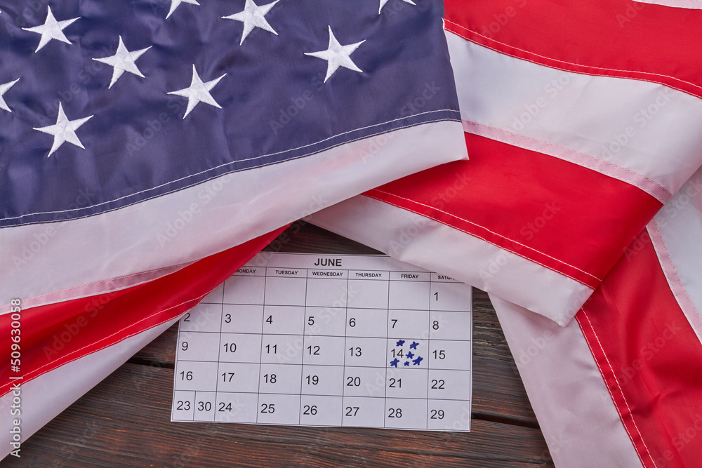 Fototapeta premium United states flag with calendar with marked june 14th. Top view flat lay.