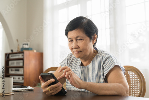 Chinese Senior adult woman sitting using smartphone at home photo