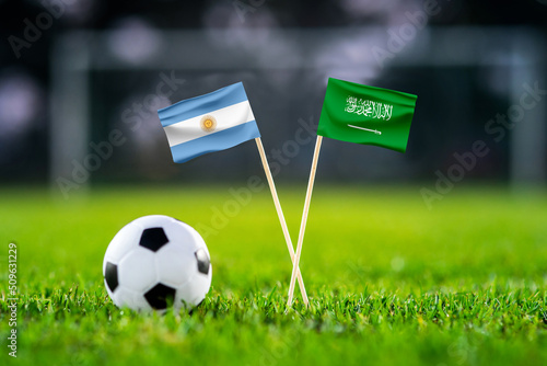 Argentina vs. Saudi Arabia, Lusail,, Football match wallpaper, Handmade national flags and soccer ball on green grass. Football stadium in background. Black edit space. photo