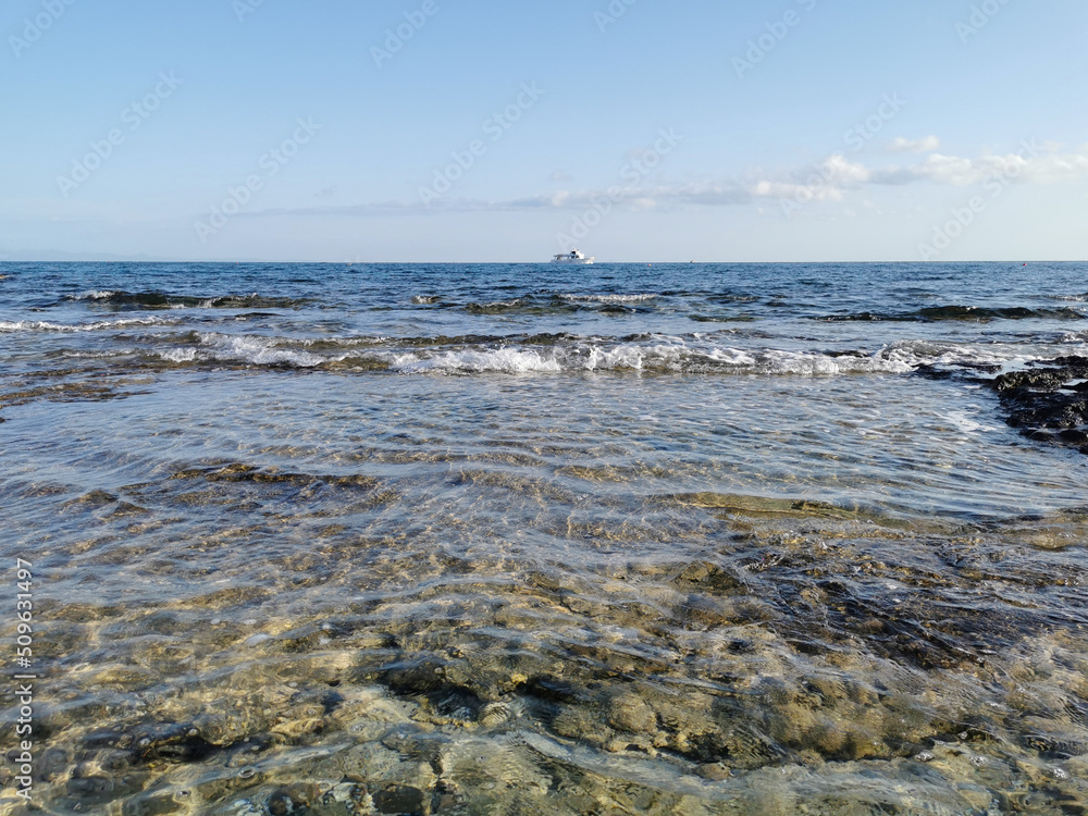 Fototapeta premium The Mediterranean Sea, in which a white pleasure yacht floats against a blue sky with clouds.