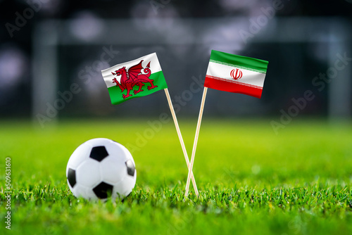 Wales vs. Iran, Ahmad Bin Ali, Football match wallpaper, Handmade national flags and soccer ball on green grass. Football stadium in background. Black edit space.