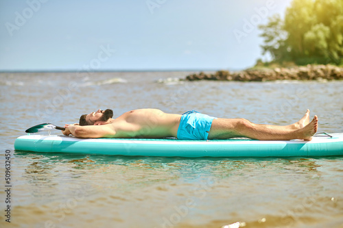 A man in blue swim wear lying on a kaya and sunbathing