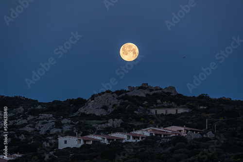 moon setting behind some mountains