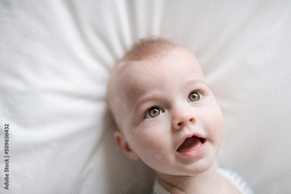 Adorable baby boy in white sunny bedroom in the morning at home Adorable baby boy in white sunny bedroom in the morning at home